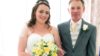 A woman in a wedding dress holding a bouquet of flowers standing next to her dad