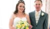 A woman in a wedding dress holding a bouquet of flowers standing next to her dad