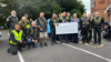 A group of bikers in a car park presenting a large cheque