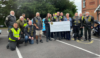 A group of bikers in a car park presenting a large cheque