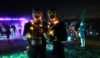 Two people in darkness wearing glow sticks and lights